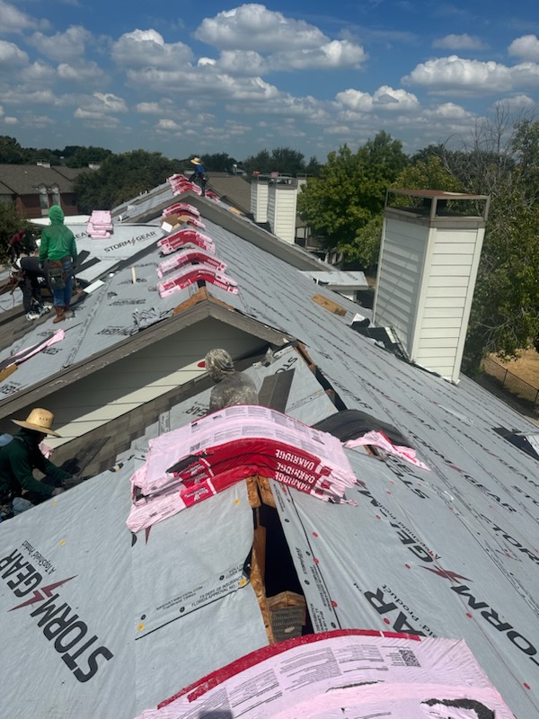 Multi-unit residential roofing installation in progress in Dallas-Fort Worth area, showing professional roofers installing underlayment and roofing materials on townhouse complex